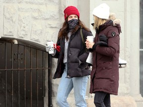 Women wearing masks and carrying coffee cups on Osborne Street in Winnipeg on Sunday, Jan. 17, 2021.