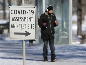 A person walks past a sign for a Covid-19 testing site, in Winnipeg on Tuesday, Jan. 19, 2021.