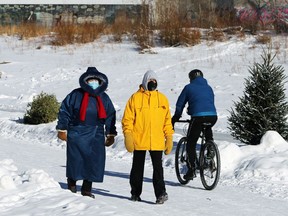 A colourful couple of walkers are passed by a cyclist on the Assiniboine River in Winnipeg on Sunday.