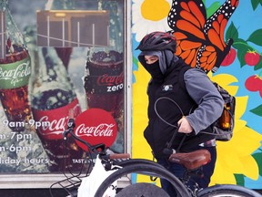 A cyclist secures their ride outside a Maryland Street grocery store in Winnipeg on Monday, Jan. 25, 2021.