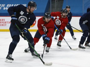 Pierre-Luc Dubois (left) looks to get a pass through to Trevor Lewis (right) during Jets practice on Monday.