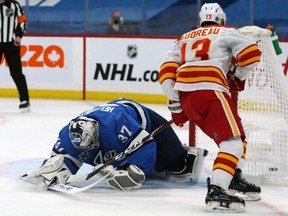 Calgary Flames forward Johnny Gaudreau tucks the puck between the legs of Jets goaltender Connor Hellebuyck for the winning shootout goal in Winnipeg last night.  
Kevin King/Winnipeg Sun