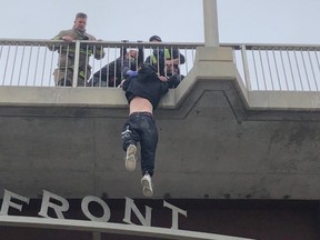 This dramatic image shows Winnipeg Police Service and the Winnipeg Fire Paramedic Service save a man’s life by bringing him to safety on the Disraeli Bridge at Higgins Avenue on Tuesday. WPS handout