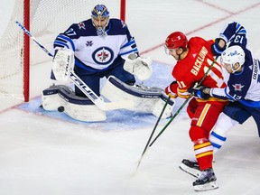 Feb 9, 2021; Calgary, Alberta, CAN; Winnipeg Jets goaltender Connor Hellebuyck (37) guards his net as Calgary Flames center Mikael Backlund (11) and Winnipeg Jets center Pierre-Luc Dubois (13) battle for the puck during the first period at Scotiabank Saddledome. Mandatory Credit: Sergei Belski-USA TODAY Sports