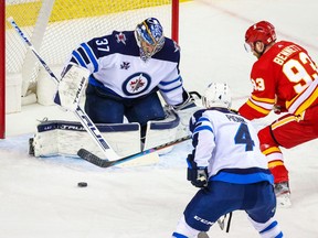 Feb 9, 2021; Calgary, Alberta, CAN; Winnipeg Jets goaltender Connor Hellebuyck (37) makes a save as Calgary Flames center Sam Bennett (93) tries to score during the first period at Scotiabank Saddledome. Mandatory Credit: Sergei Belski-USA TODAY Sports