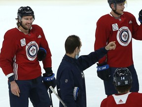 Winnipeg Jets defenceman Tucker Poolman (left) smiles as assistant coach Jamie Kompon explains a drill during an optional practice at Bell MTS Place. Poolman returned to practice for the first time since Jan. 15 on Sunday.