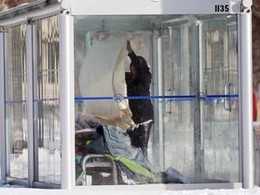 A woman folds bedding in a bus shack on Broadway in Winnipeg on Wednesday, Feb. 10, 2021.