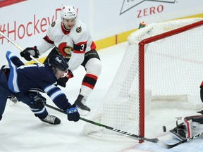 Winnipeg Jets defenceman Neal Pionk (left) scores a wraparound goal past Marcus Hogberg of the Ottawa Senators in Winnipeg on Thursday, Feb. 11, 2021.