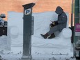A person uses a mobile device on Saturday while sitting on a sofa carved from snow, the Snowfa is part of an art project in downtown Winnipeg.