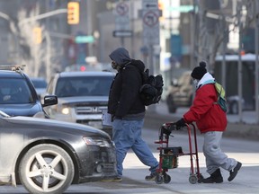 Two people in masks walk across Portage Avenue in Winnipeg on Wednesday, Feb. 17, 2021. Chris Procaylo/Winnipeg Sun