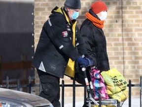 Two people wear masks while walking along a street, in Winnipeg on Friday.