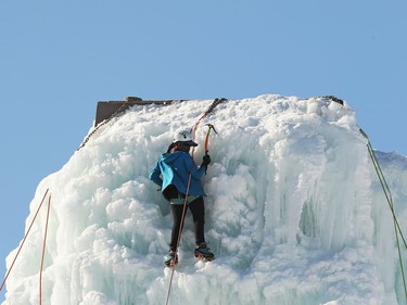 A masked ice climber looks down from the top of the structure at the Club d'escalade Saint-Boniface in Winnipeg in Winnipeg on Sunday, Feb. 21, 2021.