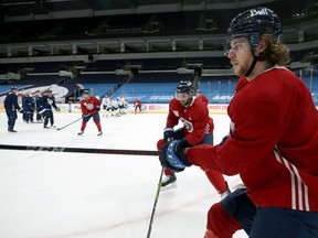 Nathan Beaulieu (right) clears the puck during Winnipeg Jets practice at Bell MTS Place in Winnipeg on Tuesday, Feb. 23, 2021.