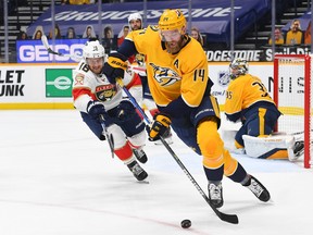 Nashville Predators defenceman Mattias Ekholm (14) skates the puck out of the defensive zone past Florida Panthers center Aleksander Barkov (16) during the second period at Bridgestone Arena in Nashville on March 4, 2021.