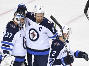 Winnipeg Jets goalie Connor Hellebuyck (37) celebrates with forward Blake Wheeler (26) after a victory over the Calgary Flames at Scotiabank Saddledome in Calgary on Monday, March 29, 2021.
