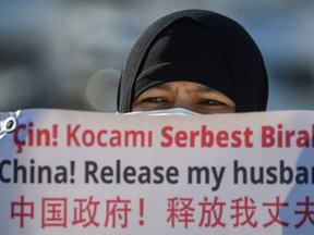 A member of the Uighur minority holds a placard as they demonstrate to ask for news of their relatives and to express their concern about the ratification of an extradition treaty between China and Turkey, Feb. 22, 2021 near the China consulate in Istanbul, Turkey.