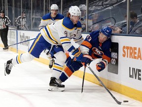 Jack Eichel of the Buffalo Sabres checks Casey Cizikas of the New York Islanders into the boards at the Nassau Coliseum on March 7, 2021 in Uniondale, New York.