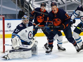 Oilers forward Jesse Puljujarvi celebrates in front of Jets goaltender Connor Hellebuyck after Connor McDavid (not pictured) scores in the first period on Saturday night in Edmonton.