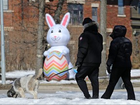 Dog-walkers pass a giant Easter Bunny on Wellington Crescent at Campbell Street in Winnipeg on Mon., April 2, 2018.
