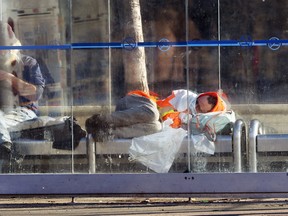 A man curls up in a bus shelter on Main Street in Winnipeg on Mon., Dec. 7, 2020. Kevin King/Winnipeg Sun/Postmedia Network