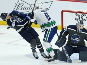 Vancouver Canucks forward J.T. Miller (centre) drops Winnipeg Jets forward Mason Appleton as goaltender Laurent Brossoit deals with a shot on Tuesday night.