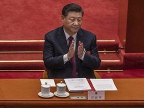 China's President Xi Jinping applauds after voting during a session that also included a vote in favour of a resolution to overhaul Hong Kong's electoral system, during the closing session of the National People's Congress at the Great Hall of the People in Beijing, March 11, 2021.