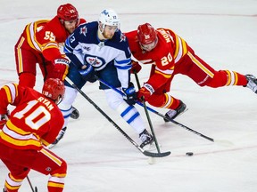 Winnipeg Jets center Pierre-Luc Dubois (13) controls the puck against the Calgary Flames during the second period at Scotiabank Saddledome in Calgary on Saturday, March 27, 2021.