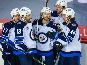 Winnipeg Jets left wing Kyle Connor (center) celebrates his goal with teammates against the Calgary Flames during the second period at Scotiabank Saddledome in Calgary on Friday, Mrch 26, 2021.
