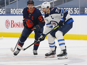 Winnipeg Jets forward Blake Wheeler (26) and Edmonton Oilers forward Connor McDavid (97) look for a loose puck during the third period  at Rogers Place in Edmonton on Saturday, March 20, 2021.