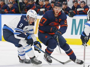 Edmonton Oilers forward Connor McDavid (97) and Winnipeg Jets forward Andrew Copp (9) chase a loose puck during the first period at Rogers Place i Edmonton on March 20, 2021.