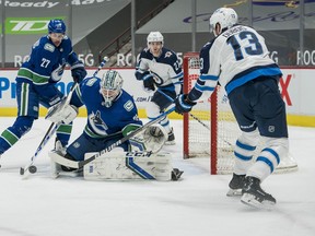 Vancouver Canucks defenseman Travis Hamonic (27) looks on as goalie Thatcher Demko (35) makes a save on Winnipeg Jets forward Pierre-Luc Dubois (13)  in the first period at Rogers Arena in Vancouver on Wednesday, March 24, 2021.