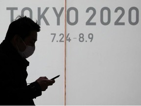 A man wearing a protective face mask, following an outbreak of the coronavirus, walks past an advertising billboard of Tokyo Olympics 2020, near the Shinjuku station in Tokyo, Japan, March 3, 2020.