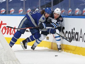 Paul Stastny #25 of the Winnipeg Jets is checked against the boards by Justin Holl #3 of the Toronto Maple Leafs during their game at Scotiabank Arena on March 9, 2021 in Toronto, Ontario, Canada.