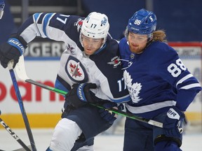 Adam Lowry (17) of the Winnipeg Jets is held up by William Nylander (88) of the Toronto Maple Leafs during their game at Scotiabank Arena on March 13, 2021 in Toronto.