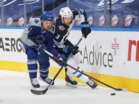 Tucker Poolman (3) of the Winnipeg Jets and Auston Matthews (34) of the Toronto Maple Leafs battle for the puck during their game game at Scotiabank Arena on March 9, 2021 in Toronto.