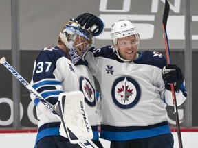 VANCOUVER, BC - MARCH 22: Goalie Connor Hellebuyck #37 of the Winnipeg Jets celebrates with teammate Paul Stastny #25 after defeating the Vancouver Canucks 4-0 in NHL action at Rogers Arena on March 22, 2021 in Vancouver, Canada.