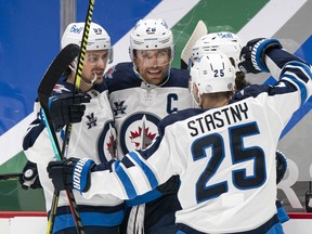 Blake Wheeler (26) of the Winnipeg Jets celebrates with teammates Mark Scheifele (55) and Paul Stastny (25) after scoring a goal against the Vancouver Canucks during the first period of NHL action at Rogers Arena on March 22, 2021 in Vancouver.
