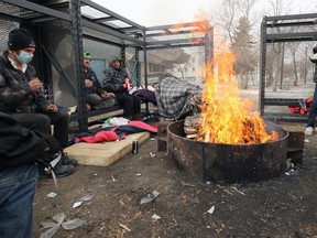 Roger West (green hat, third from left) and others stay warm by a fire outside Circle of Life Thunderbird House in Winnipeg on Wed., Feb. 24, 2021. Kevin King/Winnipeg Sun/Postmedia Network