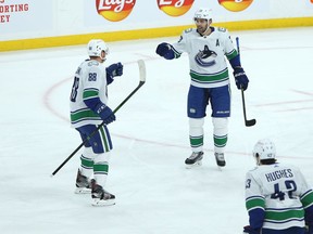 Vancouver Canucks defenceman Nate Schmidt (left) is congratulated for his goal against the Winnipeg Jets in Winnipeg by Brandon Sutter (centre) and Quinn Hughes on Monday, March 1, 2021.