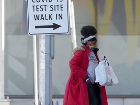 A person walks past a sign for a COVID-19 Test Site, in Winnipeg on Friday, March 5, 2021.