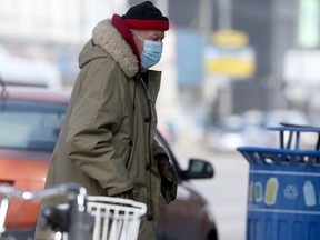 A person wears a mask while walking along a street, in Winnipeg on Saturday March 6, 2021.