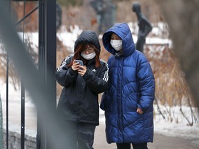 Two people look at a phone in Assiniboine Park in Winnipeg on Sunday.