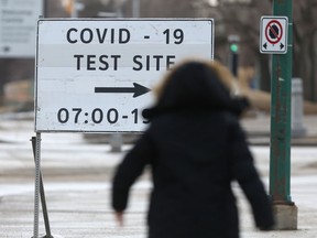 A person walks towards a sign for a COVID-19 test site, in Winnipeg on Tuesday, March 9, 2021.