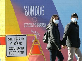 A couple wearing masks walk near a COVID-19 testing site in downtown Winnipeg on Monday, March 8, 2021.