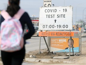 A person walks near a sign for the COVID-19 testing site on Nairn Avenue in Winnipeg on Wed., March 10, 2021. Kevin King/Winnipeg Sun/Postmedia Network