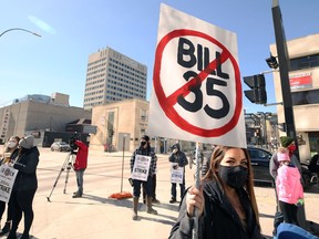 A woman carries a sign during a rally at Manitoba Hydro Place in downtown Winnipeg on Sunday.