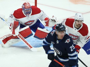 Montreal Canadiens goaltender Carey Price (left) tracks the puck against the Winnipeg Jets in Winnipeg on Mon., March 15, 2021.