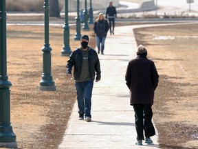 Pedestrians are mindful of one another on the Manitoba Legislative Building grounds in Winnipeg on Tuesday, March 16, 2021.