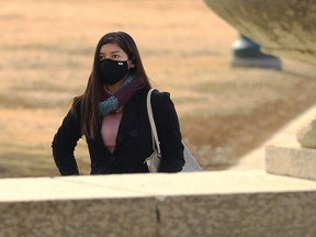 A woman wearing a mask walks on the Manitoba Legislative Building grounds in Winnipeg on Tuesday, March 16, 2021.