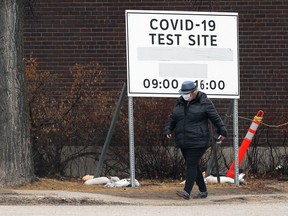 A woman walks past a COVID-19 testing site sign on St. Mary's Road in Winnipeg on Sunday, March 21, 2021.
